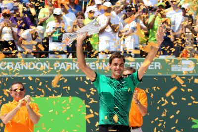 Trophy aloft -- Amazing Roger Federer -- With her head just above the Trophy -- Cell Phone in hand -- Amazing Mother of Two Sets of Twins -- Mirka Federer
== Photo: Art Seitz c2017